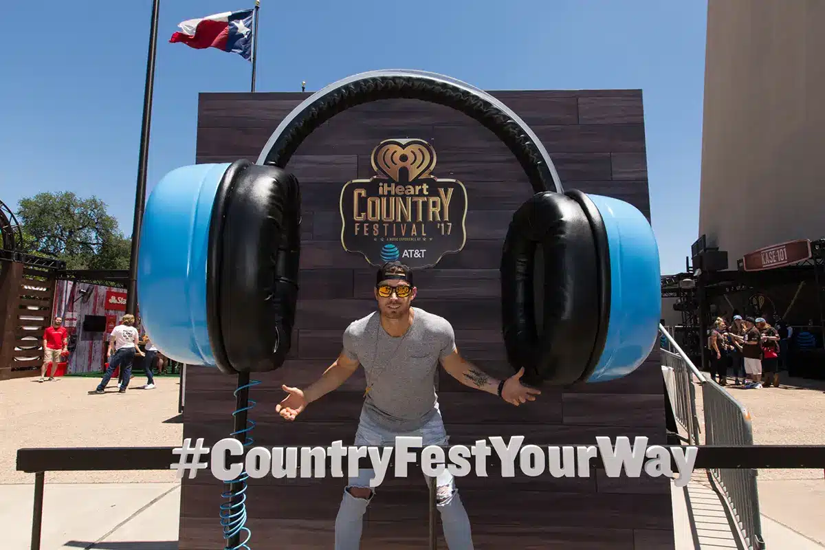 man standing in front of large head phones